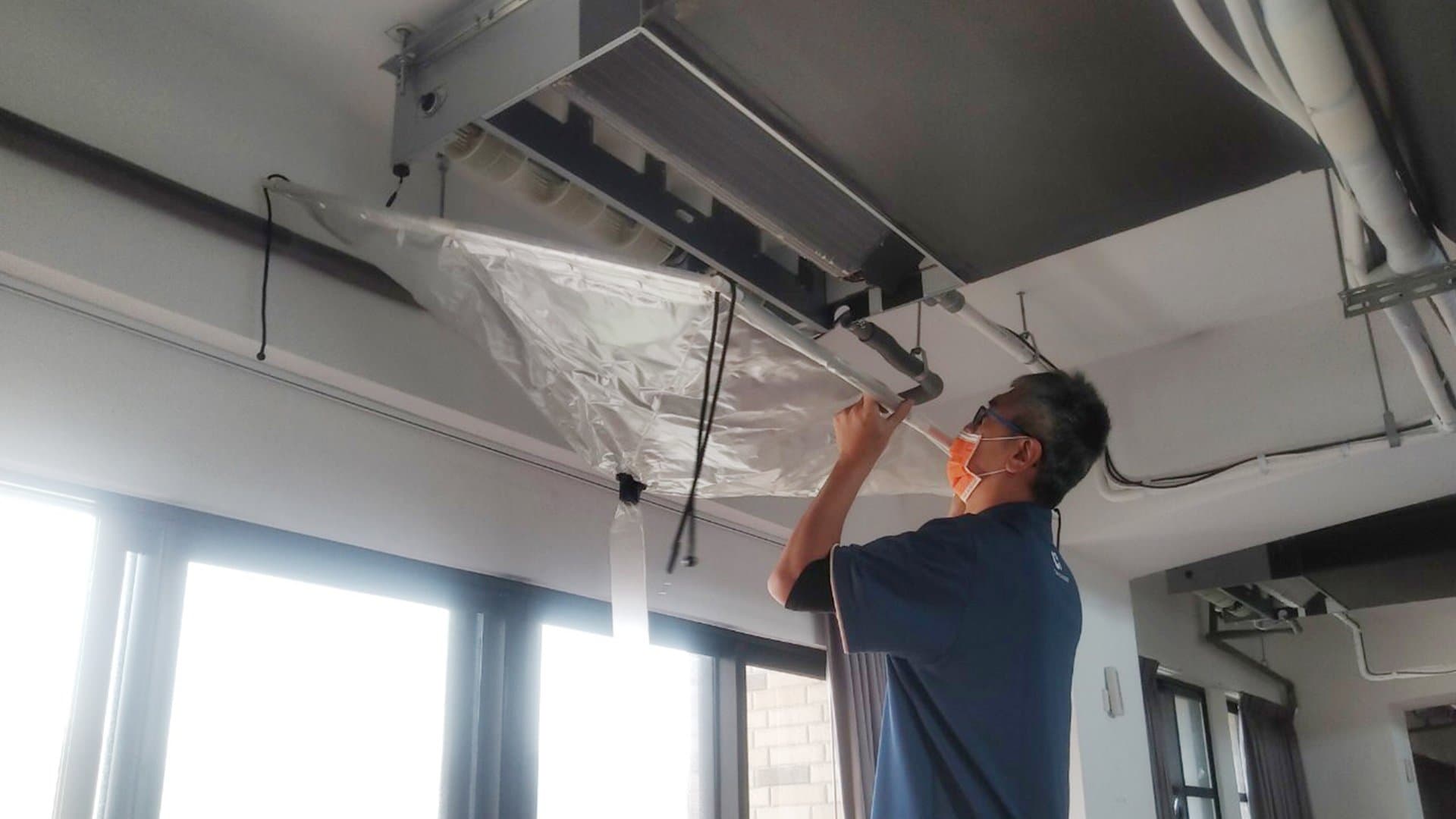 景開電器技師在天花板內進行冷氣保養作業