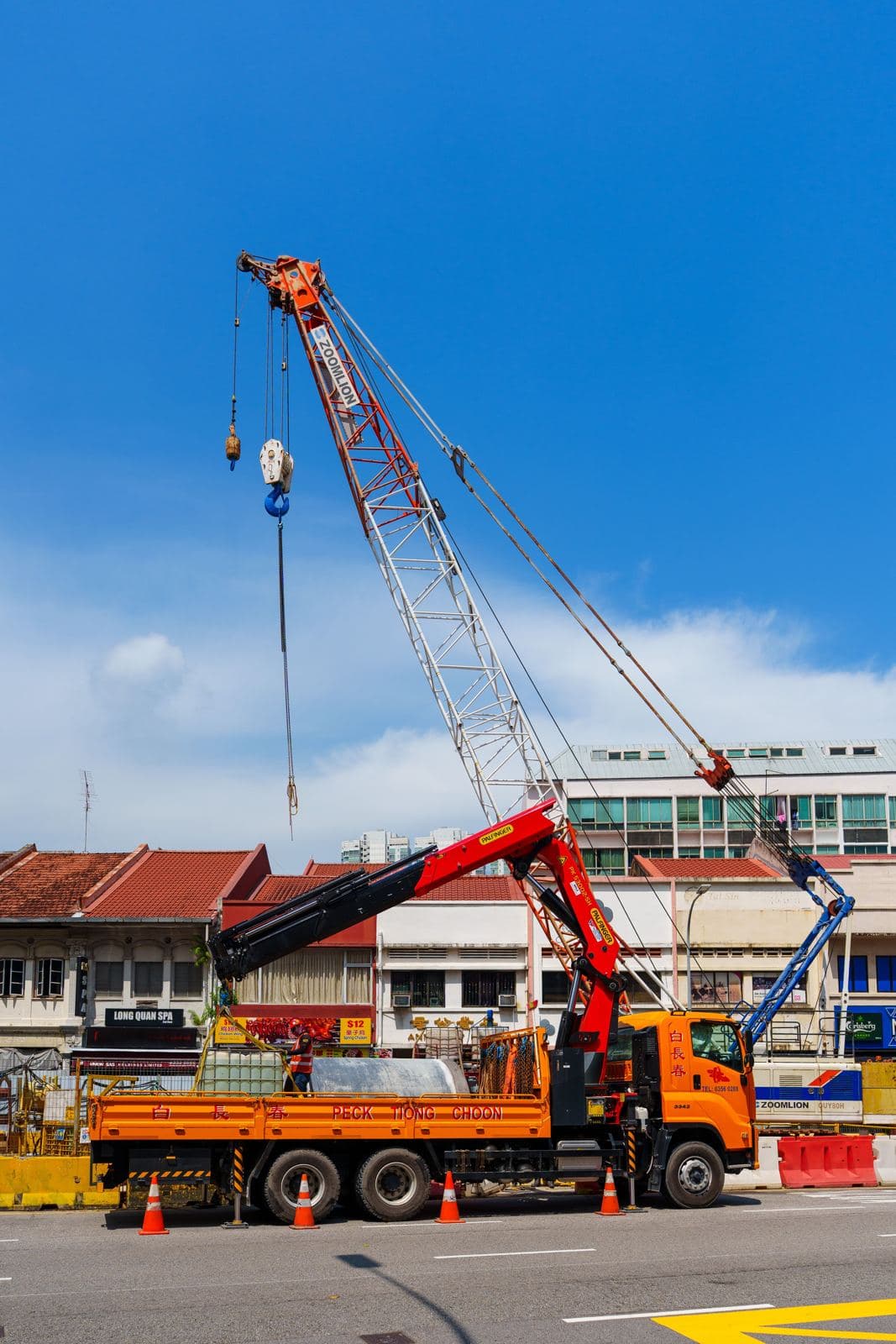 吊車於街道旁伸出吊臂,協助建築物進行高樓層設備吊裝作業
