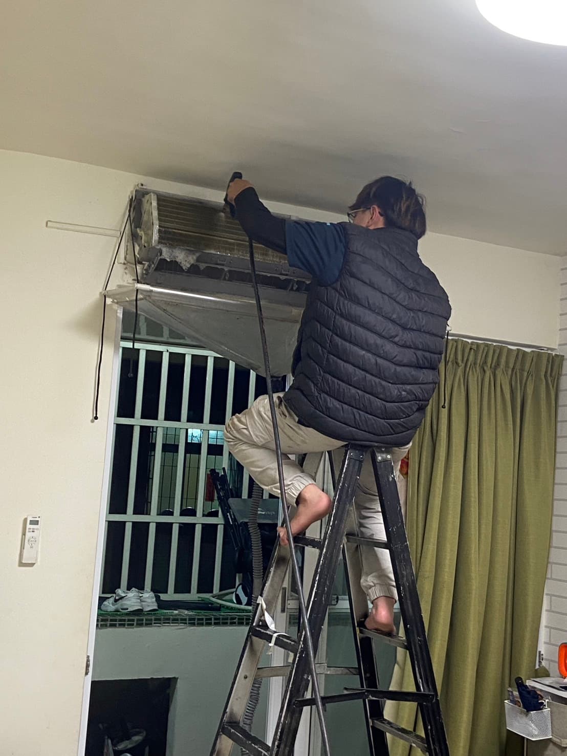 師傅站在梯上為冷氣進行保養維修